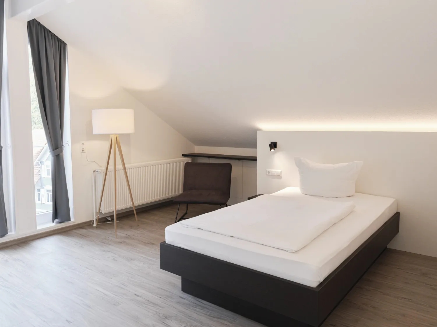 Patientenzimmer mit Bett, Vorhängen und Stehleuchte