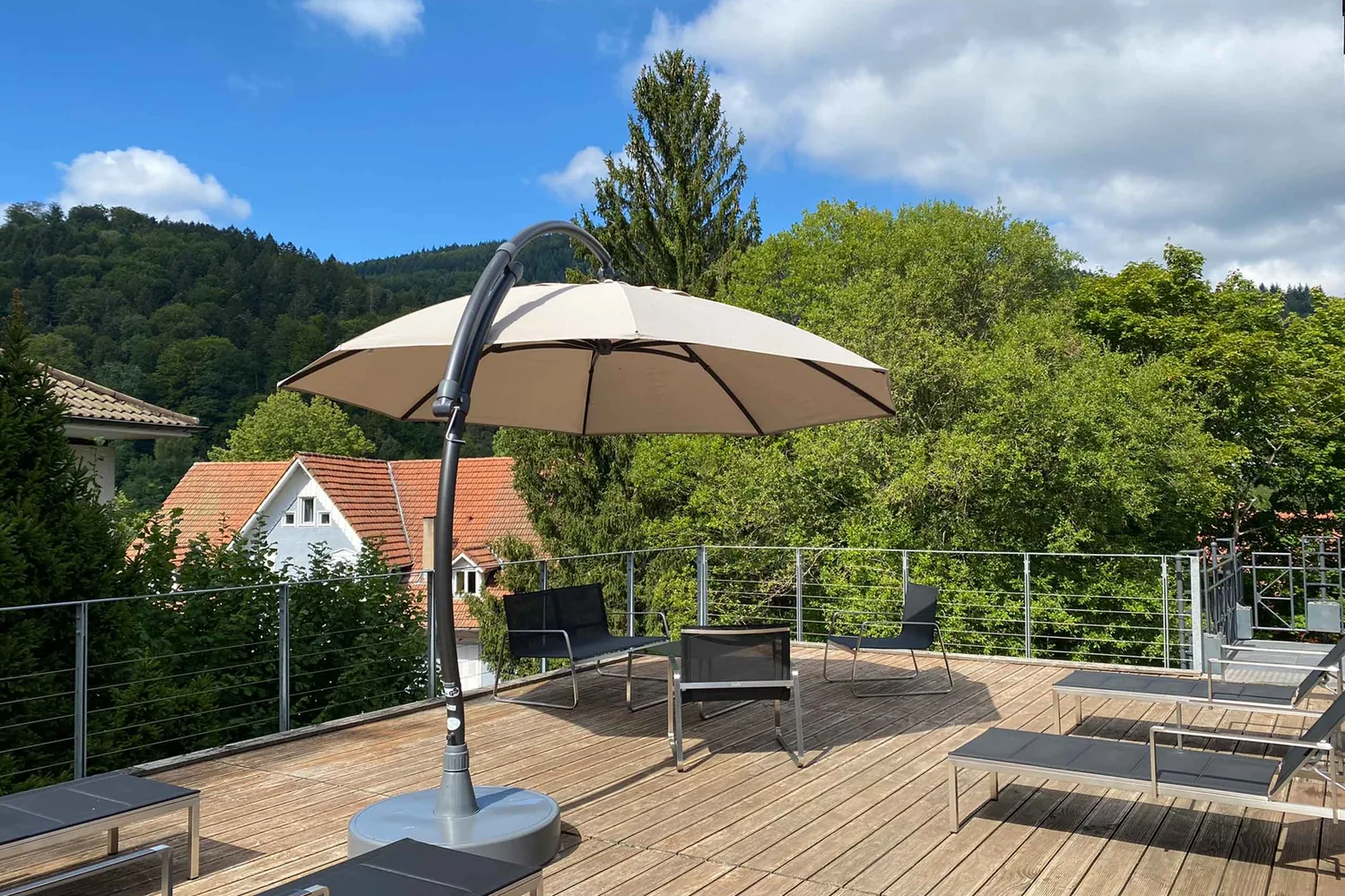Sonnige Dachterrasse mit Liegen und Sonnenschirm und Blick in den Schwarzwald